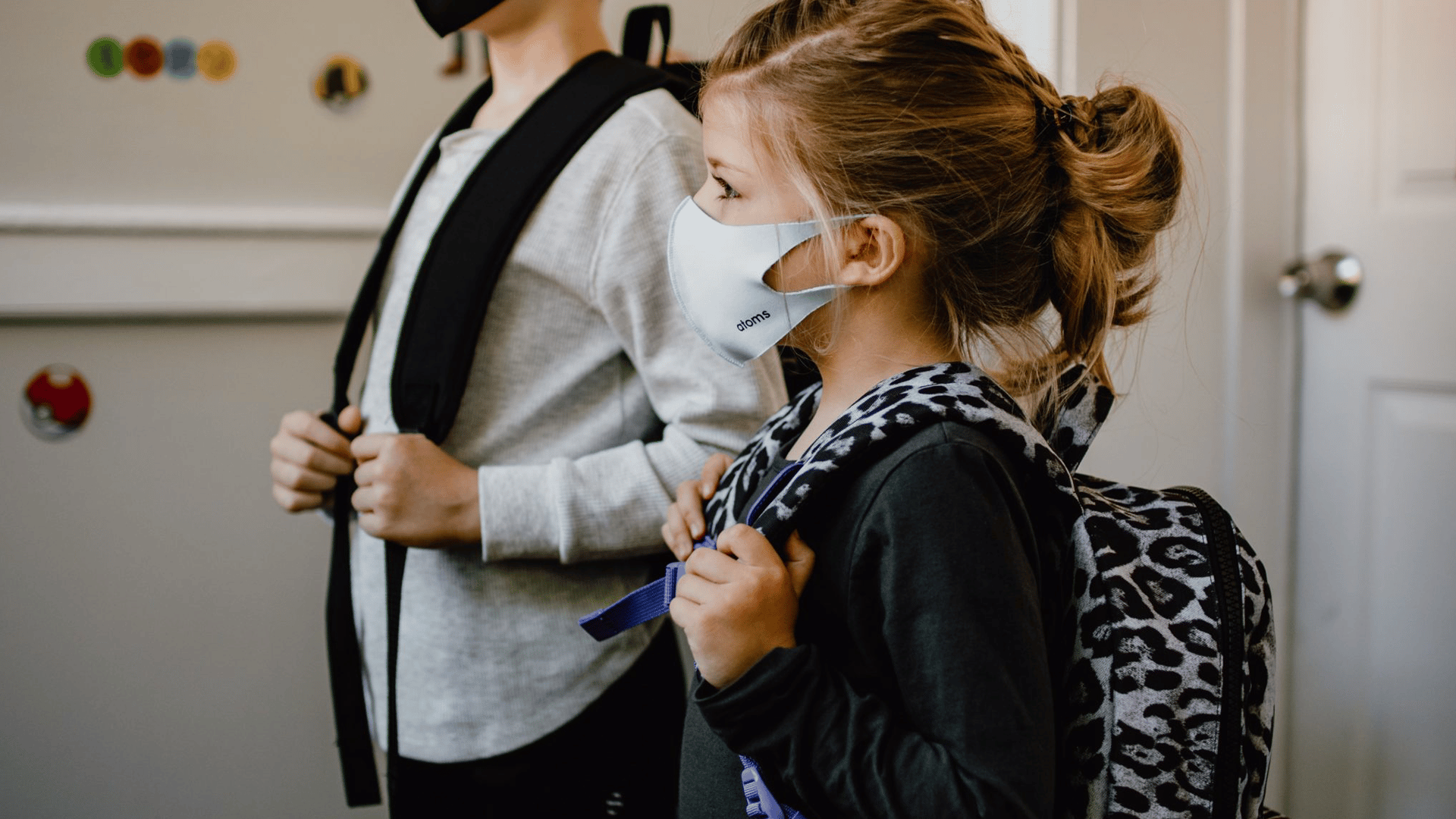 Two children with backpacks and face masks on