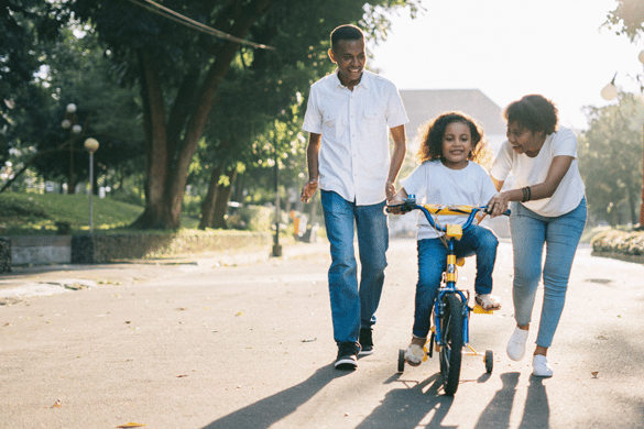 Family helping child ride a bike