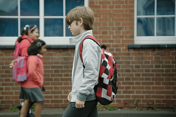 Child with backpack walking through school playground